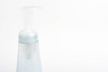 Şeffaf üst pompanın ve köpük sabun plastiğinin beyaz zemin üzerine kurulmuş bir şişesinin yakın plan resmi..