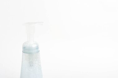 Şeffaf üst pompanın ve köpük sabun plastiğinin beyaz zemin üzerine kurulmuş bir şişesinin yakın plan resmi..