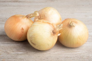 A bunch of four freshly harvested sweet white onions artfully arranged on a white painted rustic wood panel board. clipart
