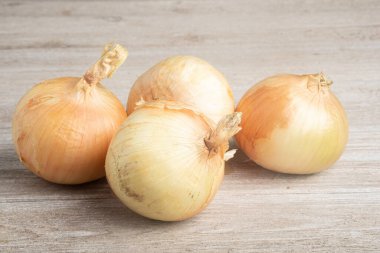 Bir demet taze toplanmış beyaz soğan ustalıkla beyaz boyalı bir ahşap panoya yerleştirilmiş..