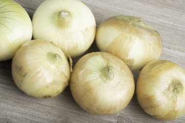 A bunch of authentic southern sweet white onions artfully arranged on a white painted rustic wood panel board. clipart