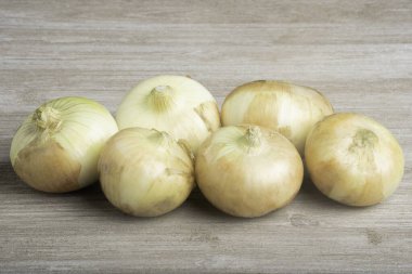 A bunch of authentic southern sweet white onions artfully arranged on a white painted rustic wood panel board. clipart