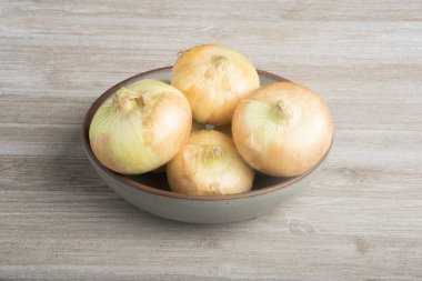 Bir grup otantik beyaz soğan ustalıkla seramik bir kaseye yerleştirilmiş beyaz boyalı bir ahşap panele yerleştirilmiş..