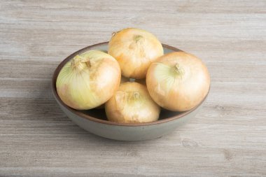 A bunch of authentic southern sweet white onions artfully arranged on a ceramic bowl placed on a white painted rustic wood panel board. clipart