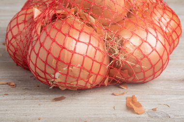 Marketlerde ve marketlerde perakende satışı için esnek kırmızı tel örgü poşetlere paketlenmiş bir avuç soğan..