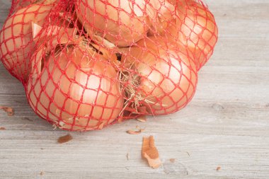 Marketlerde ve marketlerde perakende satışı için esnek kırmızı tel örgü poşetlere paketlenmiş bir avuç soğan..