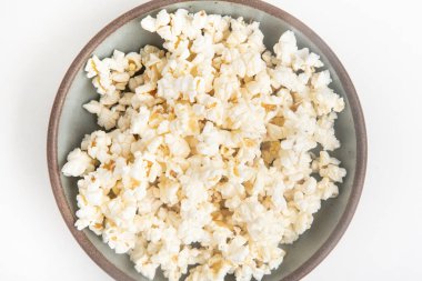 Beyaz arka planda seramik kasede patlamış mısır..