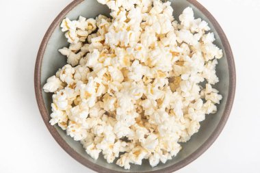 Beyaz arka planda seramik kasede patlamış mısır..