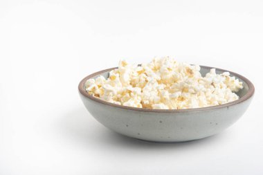 Beyaz arka planda seramik kasede patlamış mısır..