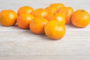 Bir grup taze portakal, beyaz desenli ahşap panoda ustalıkla düzenlenmiş..