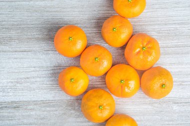 Bir grup taze portakal, beyaz desenli ahşap panoda ustalıkla düzenlenmiş..