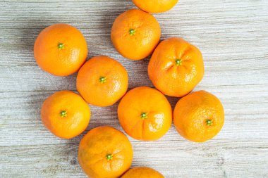 Bir grup taze portakal, beyaz desenli ahşap panoda ustalıkla düzenlenmiş..