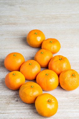 Bir grup taze portakal, beyaz desenli ahşap panoda ustalıkla düzenlenmiş..