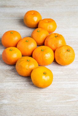 Bir grup taze portakal, beyaz desenli ahşap panoda ustalıkla düzenlenmiş..