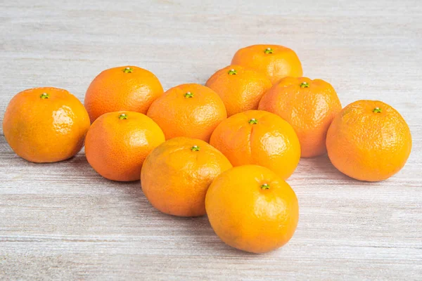 Bir grup taze portakal, beyaz desenli ahşap panoda ustalıkla düzenlenmiş..