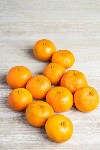 Bir grup taze portakal, beyaz desenli ahşap panoda ustalıkla düzenlenmiş..