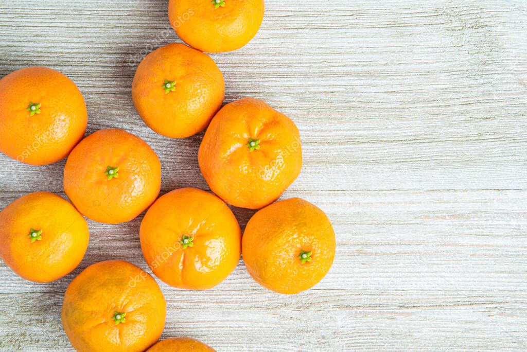 A group of fresh oranges artfully arranged on a white-painted textured wood panel board.