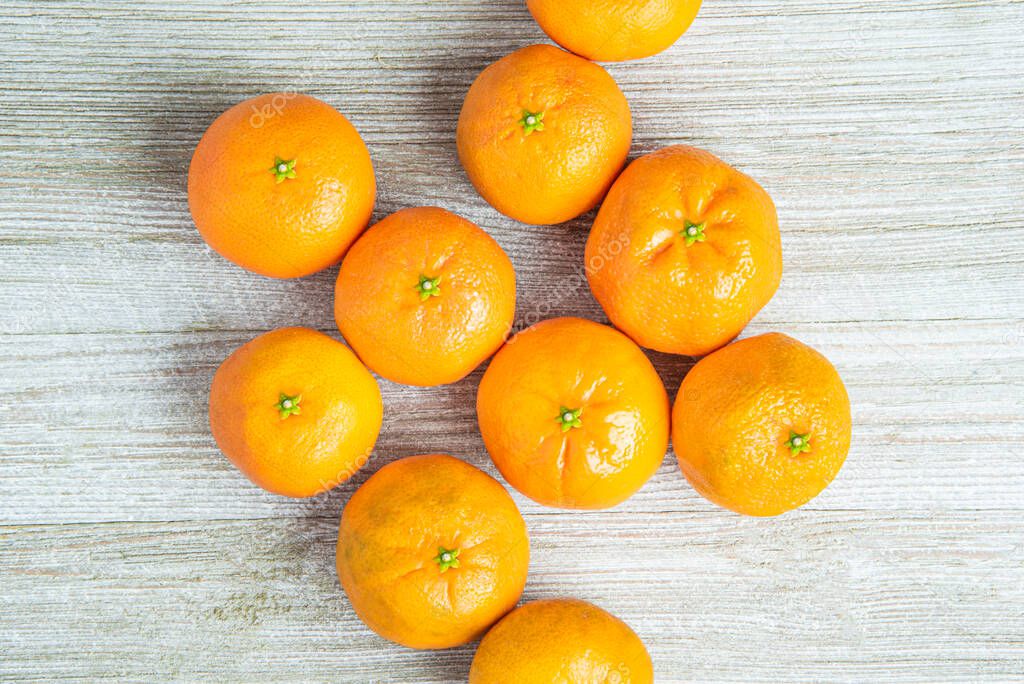 A group of fresh oranges artfully arranged on a white-painted textured wood panel board.