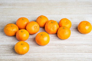 Bir grup taze portakal, beyaz desenli ahşap panoda ustalıkla düzenlenmiş..