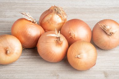 Bir demet taze, otantik güney yetiştirilmiş soğan ustalıkla beyaz boyalı bir ahşap panoya yerleştirilmiş..