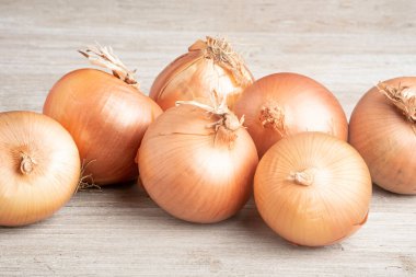 Bir demet taze, otantik güney yetiştirilmiş soğan ustalıkla beyaz boyalı bir ahşap panoya yerleştirilmiş..