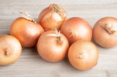 A bunch of fresh, authentic sweet southern-grown onions artfully arranged on a white painted rustic wood panel board. clipart