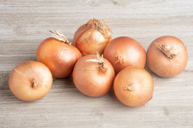 Bir demet taze, otantik güney yetiştirilmiş soğan ustalıkla beyaz boyalı bir ahşap panoya yerleştirilmiş..