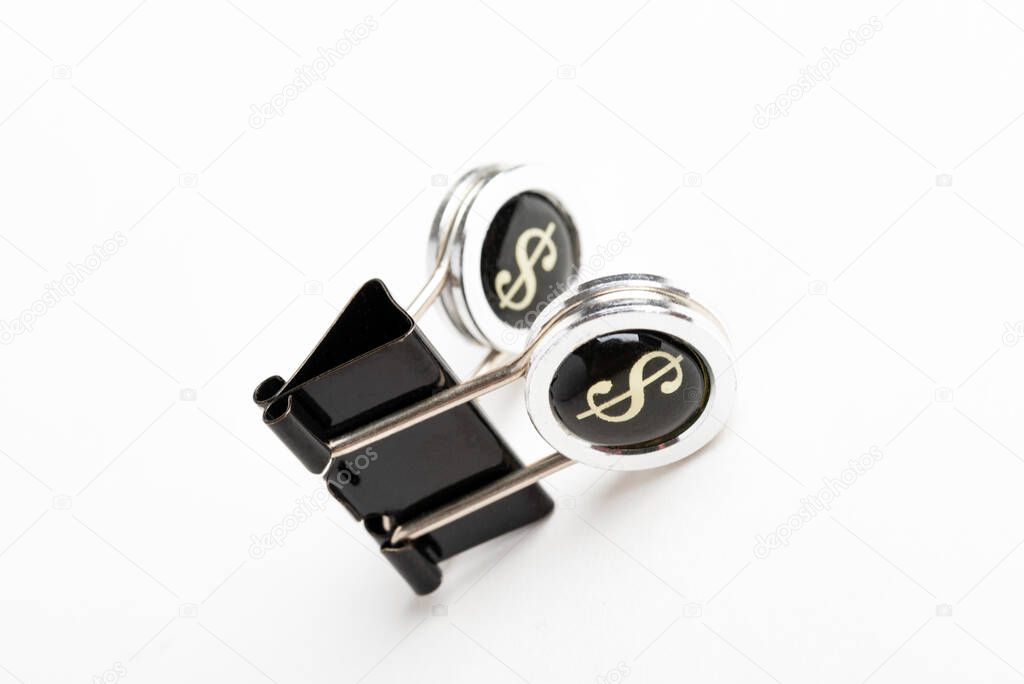 A close-up of a black document clip with circular press handle featuring a dollar sign set on a plain white background.
