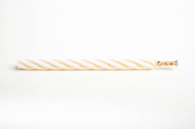 Işıksız bir tam doğum günü pastasının makro çekimi. Beyaz arka planda tek bir dekoratif renk girdaplı mum..