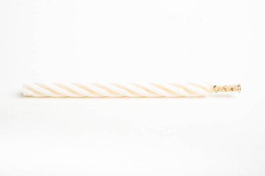 Işıksız bir tam doğum günü pastasının makro çekimi. Beyaz arka planda tek bir dekoratif renk girdaplı mum..