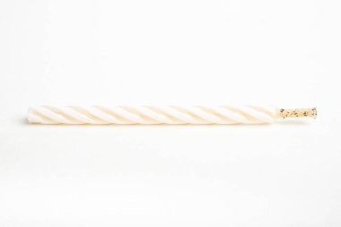 Işıksız bir tam doğum günü pastasının makro çekimi. Beyaz arka planda tek bir dekoratif renk girdaplı mum..