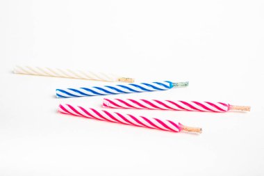 A macro shot of full, unlit birthday cake topping candles with single decorative color swirl set on a plain white background. clipart