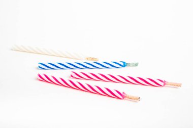 A macro shot of full, unlit birthday cake topping candles with single decorative color swirl set on a plain white background. clipart