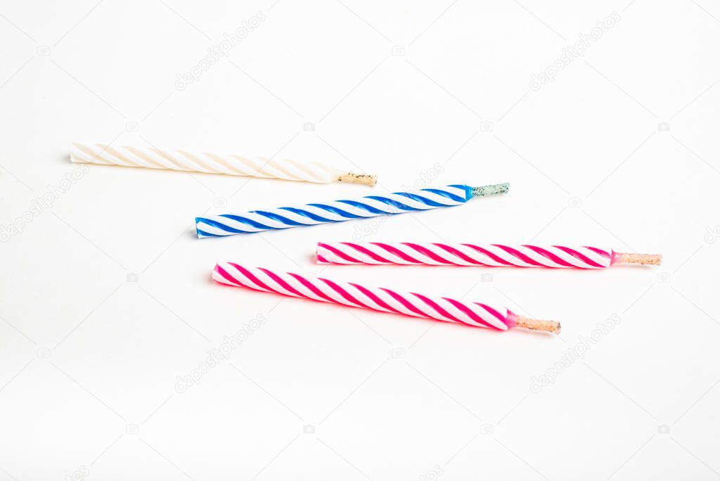 A macro shot of full, unlit birthday cake topping candles with single decorative color swirl set on a plain white background.