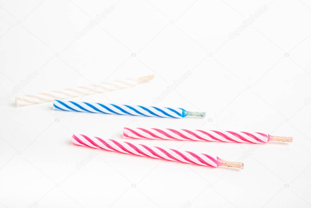 A macro shot of full, unlit birthday cake topping candles with single decorative color swirl set on a plain white background.