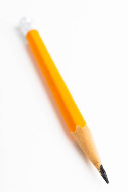Sivri uçlu sarı-turuncu altıgen kalem koçanı, beyaz kağıt üzerine seçici odaklı yakın çekim ya da makro çekim..