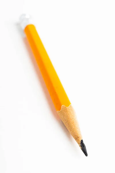 白紙を基調とした研ぎ澄まされた古典的な黄橙色の六角形の鉛筆スタブを中心としたクローズアップまたはマクロショット — ストック写真