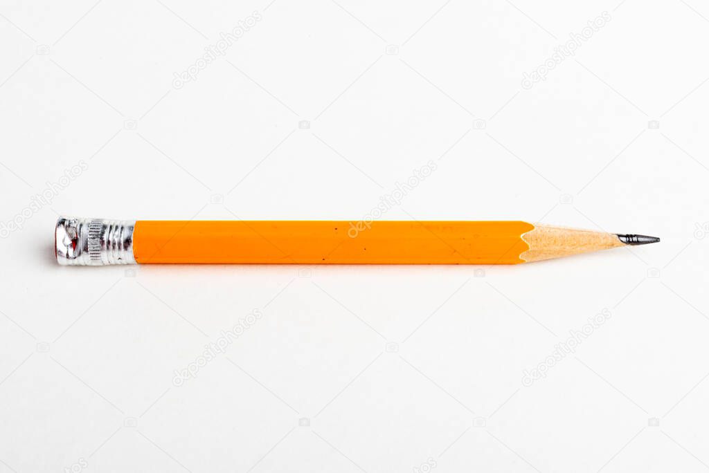 A close-up or macro shot with selective focus of a sharpened classic yellow-orange hexagonal pencil stub set on plain white paper.