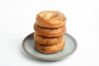 Seramik tabakta sade beyaz zemin üzerine seramik simit serpiştirilmiş 4 'lük bir yığın.. 