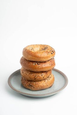 Seramik tabakta sade beyaz zemin üzerine seramik simit serpiştirilmiş 4 'lük bir yığın.. 