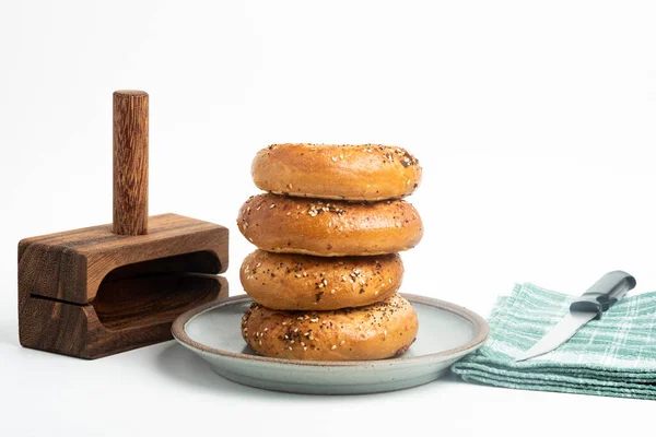 Seramik tabakta dört adet yeni pişmiş simit ve sade beyaz arka planda bir tahta ve bıçak seti..