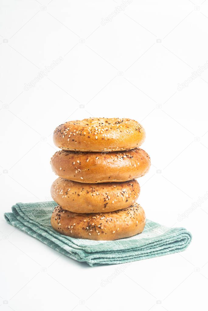 A single tall stack of four freshly baked bagels on a green napkin set on a plain white background.