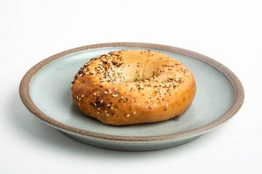 Beyaz arka planda seramik tabakta taze pişmiş tek bir simit..