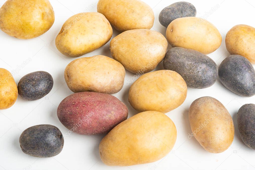 An assorted color raw and fresh potatoes artfully arranged and set on flat white surface table background.