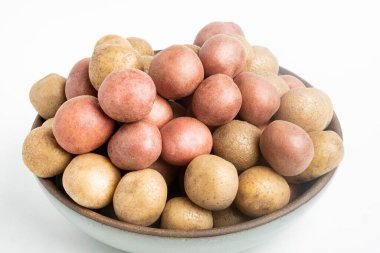 Çiğ ve taze bebek patatesler ustalıkla bir kaseye konulmuş ve beyaz arka plan üzerine kurulmuş..