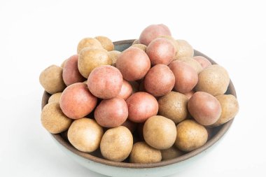 Raw and fresh baby potatoes artfully arranged in a bowl and set on white background. clipart