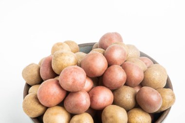 Çiğ ve taze bebek patatesler ustalıkla bir kaseye konulmuş ve beyaz arka plan üzerine kurulmuş..