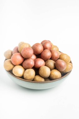 Çiğ ve taze bebek patatesler ustalıkla bir kaseye konulmuş ve beyaz arka plan üzerine kurulmuş..