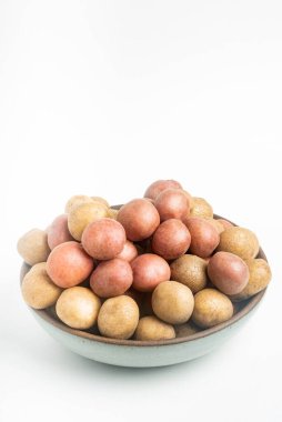 Çiğ ve taze bebek patatesler ustalıkla bir kaseye konulmuş ve beyaz arka plan üzerine kurulmuş..