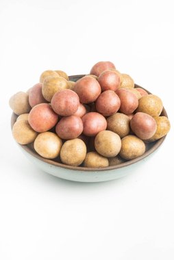 Çiğ ve taze bebek patatesler ustalıkla bir kaseye konulmuş ve beyaz arka plan üzerine kurulmuş..